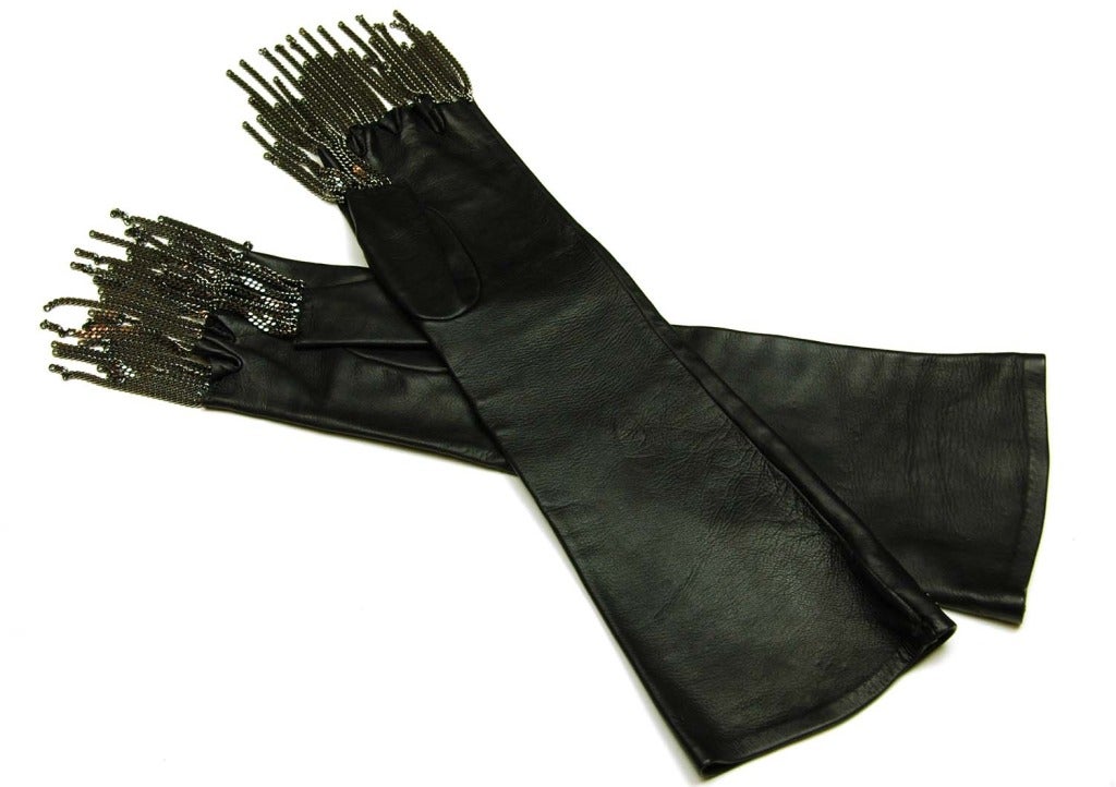 CHANEL Fingerless Black Leather Gloves W. Silver Chain Fringe c. 2011
Age: 2011
Made in France
Materials: leather, silver chain.
Features long, fingerless gloves in smooth black leather with silver chain link stripes and fringe over fingers.