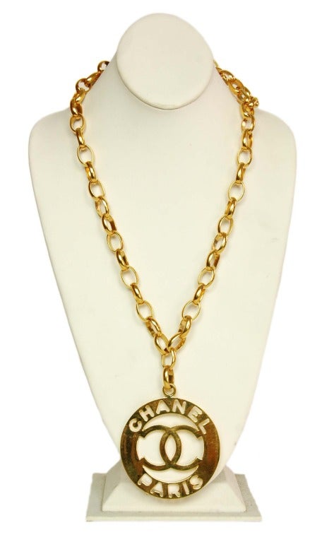 Made in France
Materials: goldtone metal.
Features long, goldtone chainlink necklace with oversized circular medallion. Medallion has a large CC logo and a banner that reads CHANEL PARIS in cutout letters. Hook and eye closure, length of necklace