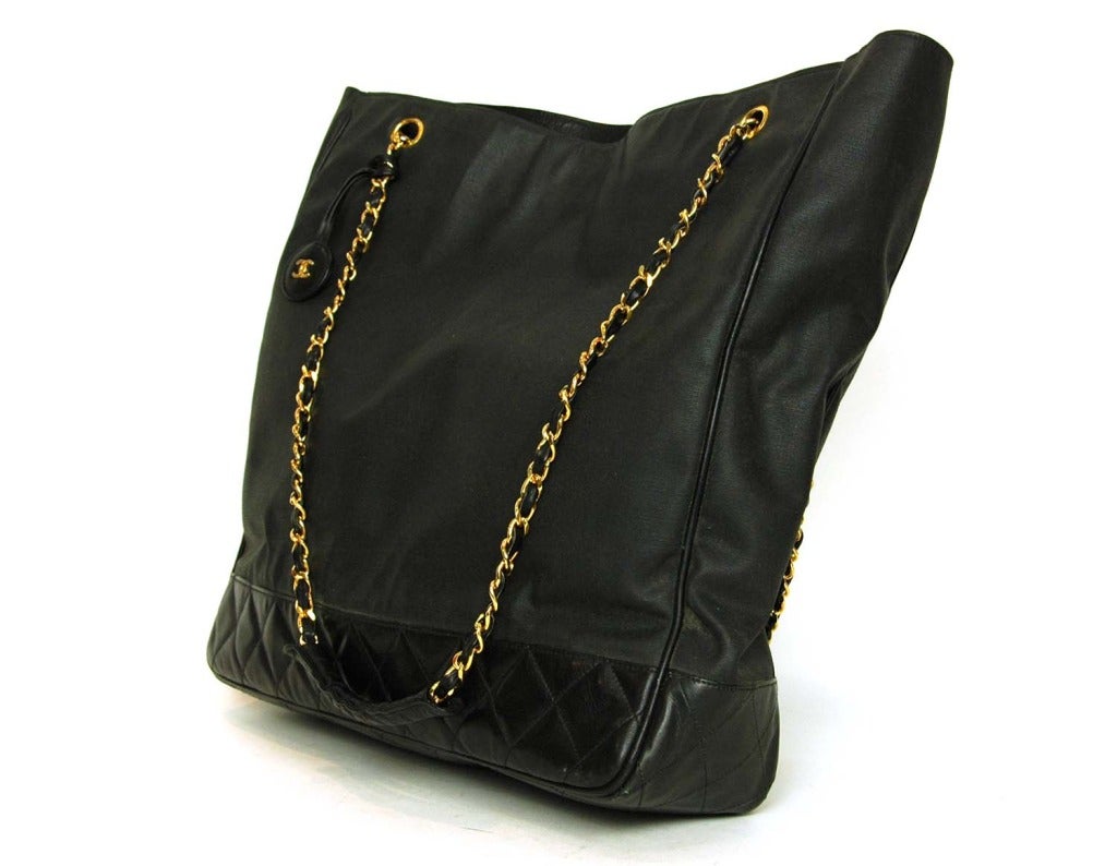 Chanel Black Canvas/Leather Tote W/Double Chain 

Age: c. 1986-1988
Made in Italy
Materials: Canvas, leather, goldtone metal
Features two large interior zippered pockets and two snap closures
Leather charm with goldtone CC hangs from