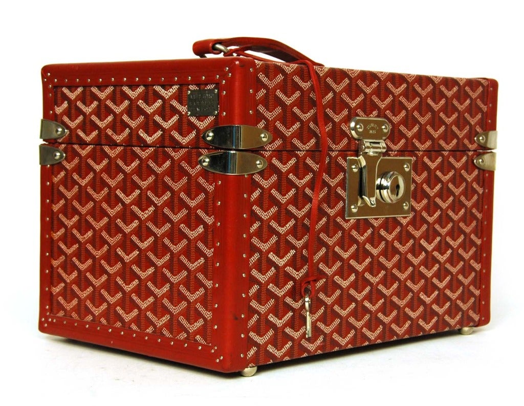 Goyard Red Hard Toiletries Case (Rt. $3,800) 

Materials: leather, silvertone metal
Comes with five bottle holders and strap for reinforcement. Also has top insert.
Closes with push in lock and key.
Small plaque on side reads 