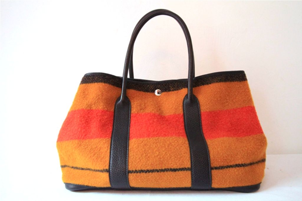 A perfect everyday bag in an eye catching color combination!<br />
<br />
Hermes Garden Party tote in rare horse blanket material. Shades of mustard and orange with black leather trim and double black rolled leather top handles. It closes with a