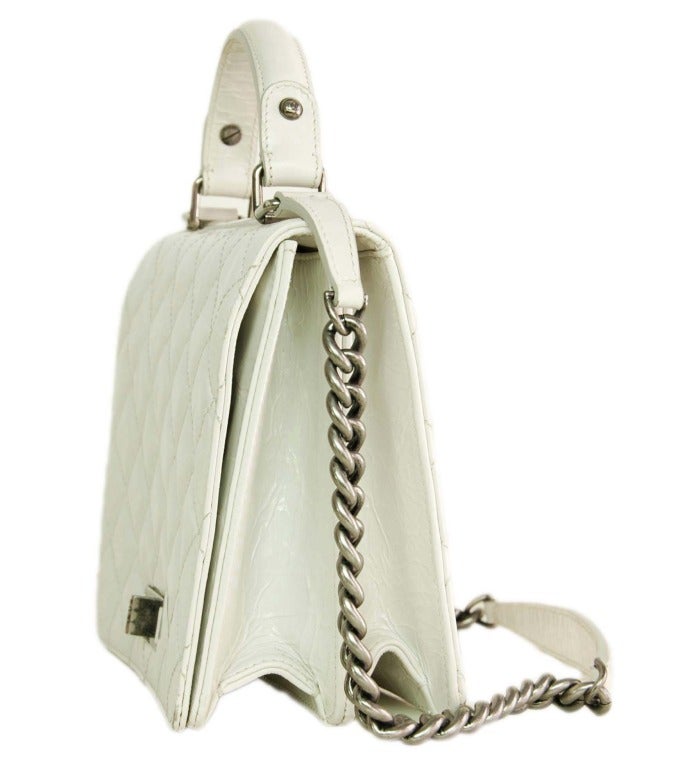 c.2011
Distressed ivory leather with antiqued silvertone hardware.
Front flap with concealed magnetic snap.
Adorned with a 2.55 twistlock.
Can be carried by top handle or chain strap.
Grey textile lining.
Interior is divided into two