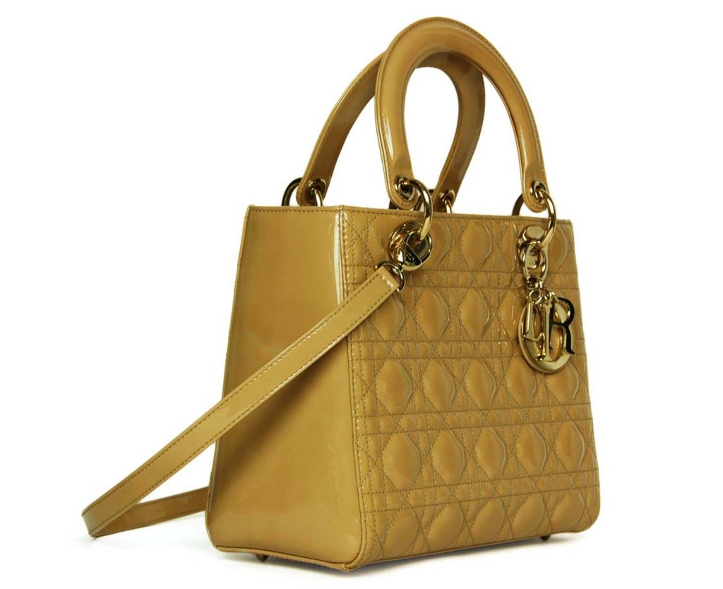 Made in Italy
Materials: beige patent leather, fabric lining, silver hardware.
Features quilted tote bag with top zipper, two short handles and one long, detachable strap (attached via lobster clasps.) Four protective metal feet at base. Dangling