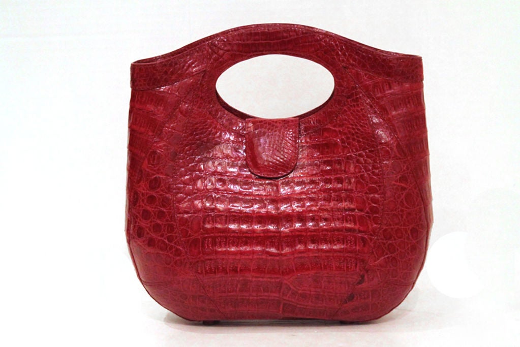 This stunning NANCY GONZALEZ Crocodile Handbag is a must-have!

Features red glazed crocodile skin. Closes with magnetic snap at handle. Four crocodile skin covered feet on the bottom of the bag. Interior of the bag has one zipper pocket, open