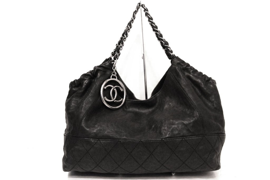 This CHANEL Coco Cabas Tote in black caviar leather with quilted stitching on the bottom of the bag is the must-have for all. Pewter-tone hardware black leather interlaced double top chain handles, with bold 