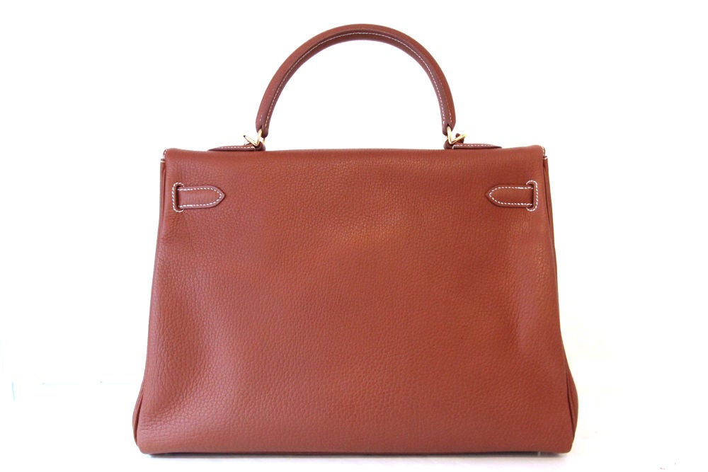 This is a timeless classic HERMES KELLY bag in beautiful Cognac.  The bag is made in fjord leather with golden hardware. Contrast stitching. Top handle with front flap and twist lock closure.  Inside the bag is lined in full leather, and there a zip