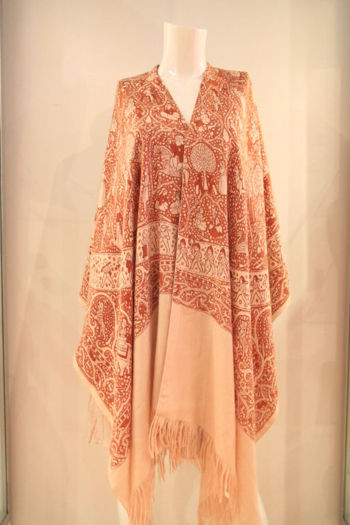 This beautiful HERMES “Lalbhai” Silk/Cashmere Poncho is a work of art.  Designed by artist Michel Duchene, the poncho is made of 65% cashmere and 35% silk.  This lightweight ivory/burnt orange poncho with fringe trim is both rare and exquisite. 