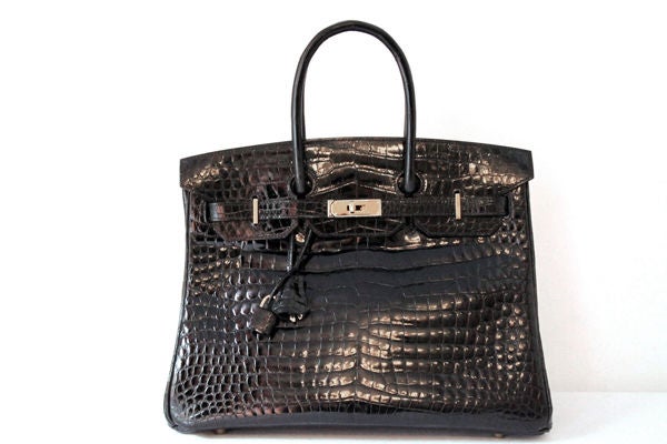 This HERMES Birkin 35cm Bag is made of black porosus crocodile leather with golden hardware.  Golden hardware on crocodile strap engraved with 