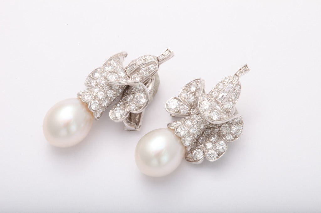 A pair of elegant diamond and drop pearl earrings by Van Cleef & Arpels. Comprising of fine  matched South Sea Cultured drops with aprox 7.58 carats of round and emerald cut diamonds. Set on Platinum. Signed and Numbered with French Hallmarks.