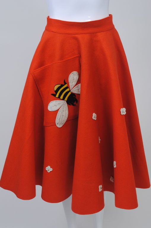 What fun! This orange felt circle skirt has an oversize bee appliqué with handstitched details over its oversized asymmetrical patch pocket. Scattered across the front of the skirt are white felt flowers with rhinestone centers. Unlined, 2