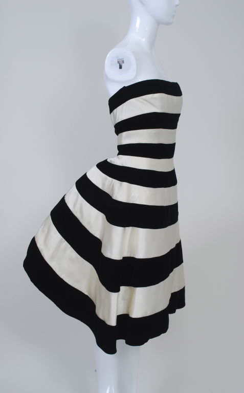 A definite statement piece! You will not go unnoticed in this dramatic Victor Costa strapless dress of white satin and black velvet stripes. From the front, it looks simple and beautiful enough, but turn slightly and you are in for a surprise. In