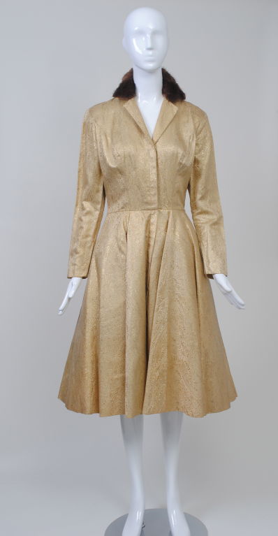 Luis Estevez designed for his Grenelle label from 1955-1968. This gold brocade shirtdress, probably from the late 1950s-early 1960s exhibits the influence of sportswear as a style adaptable to evening wear. Entry is through a front zipper. the