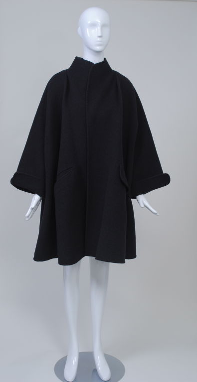 1980s charcoal wool swing coat by master cutter Geoffrey Beene has his signature rounded curves at collar and turned-back slit cuffs. Best and surprising detail are the pockets - slit on one side and flap on the other. V-shaped yoke at back and