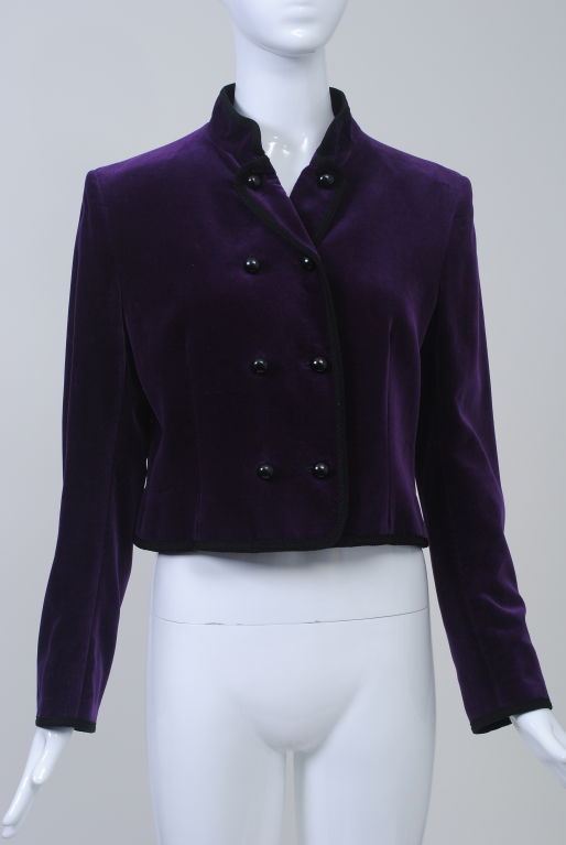 Jaeger cropped royal purple velvet jacket with black braid trim, double breasted with black globe buttons and half-mandarin, half-lapel collar, an usual touch as the lapels are secured with buttons as well. The long, straight sleeves have three