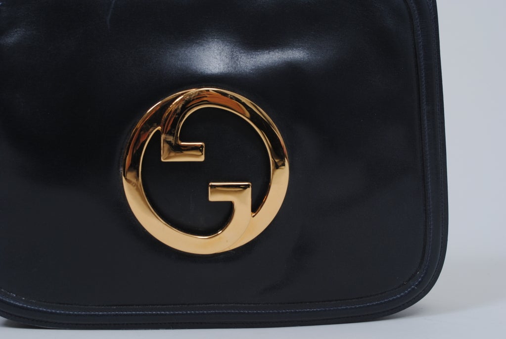 Gucci 1980s accordion-style bag has envelope flap with cut-out gold metal Gucci logo and welting detail around perimeter. The expandable interior is divided into two equal compartments and comes with a separate mirror case and identity card. Nice