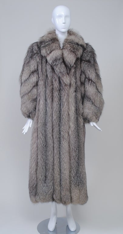 Luxurious silver fox maxi coat of high quality skins with beautiful natural coloration. The straight, slim body has vertical skins and a cross-cut shawl collar; the skins on the balloon sleeves are worked diagonally and the wrists are tapered. The