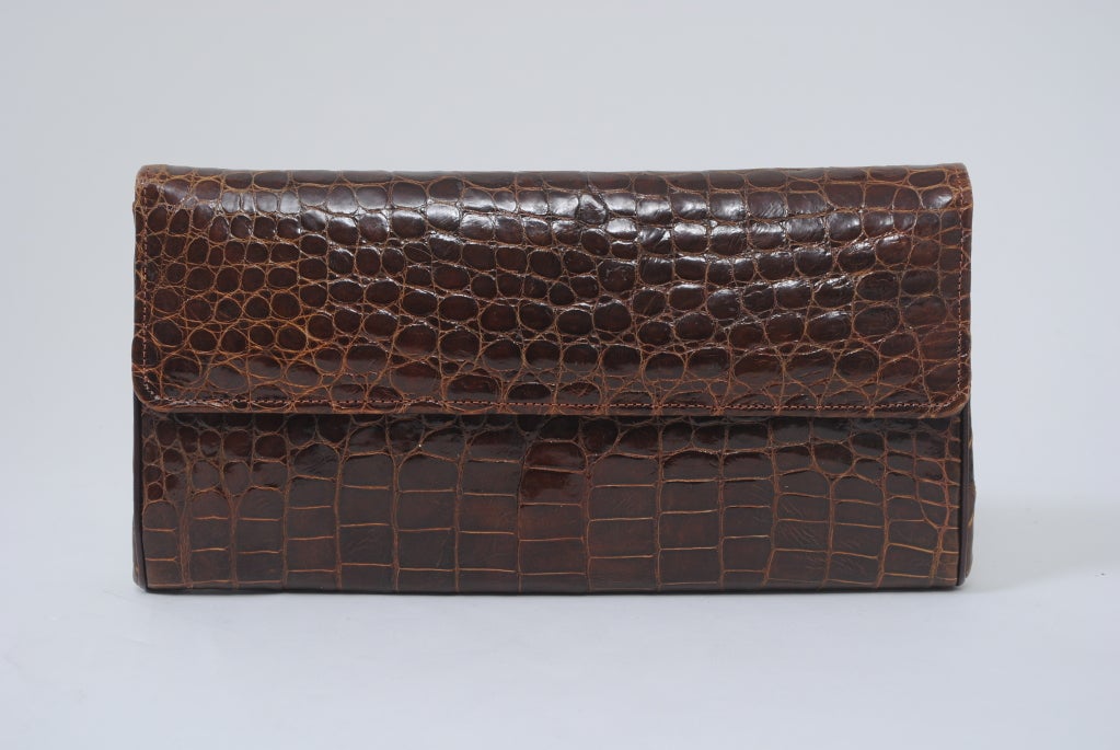 Perfect brown alligator clutch, rectangular in shape, envelope flap. Interior is brown leather with zipper compartment, two side compartments and a lipstick compartment.