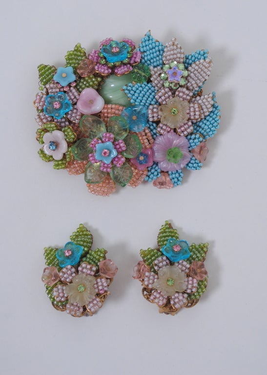 Typical of the intricate, colorful, and hand-wired creations for which Stanley Hagler jewelry is know, this brooch and earrings features an overlay of floral motifs in pastel tones of seed beads and complementary components on a filigree frame.