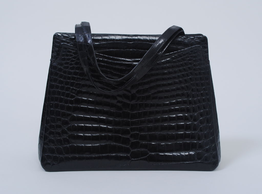 From one of the great French purveyors of luxury leather goods, this large crocodile handbag features a generous interior as well as outside compartments to perfectly accommodate your everyday necessities. It is fashioned of beautiful skins and