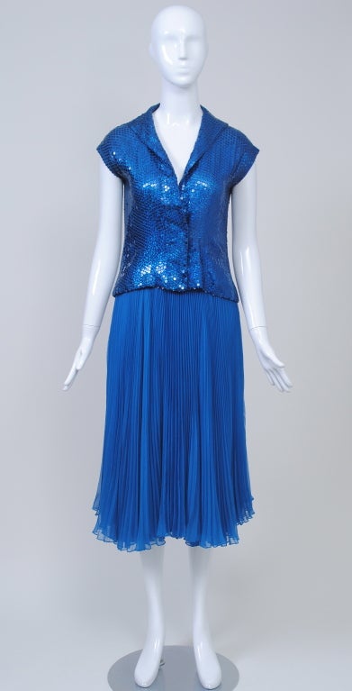 Norman Norell is well known for his sequined creations. Here is an unusual version that, though unlabeled, is unmistakably Norell.<br />
<br />
A casual style predominates, from the shirt-style top to the pleated skirt. Bright blue sequins with a