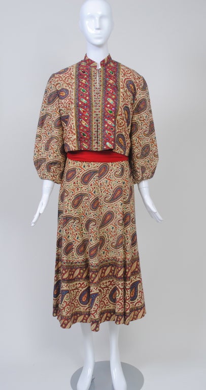 A fabulous vintage piece from the 1950s, this dress and jacket is fashioned out of an Indian paisley cotton print on a beige ground. The cropped jacket is quilted and features balloon sleeves, a Mandarin collar, and a front border that is accented