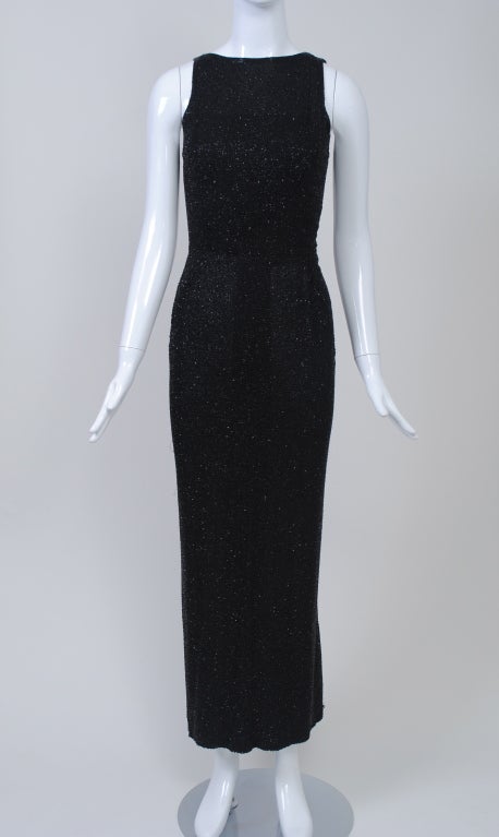 Fabulous long sheath of black crepe with allover beading in a squiggle design of black bugle beads. Narrow body hugging design with straight neckline front and back and cut-in armholes, both finished with rows of the beading. Ankle-length skirt has