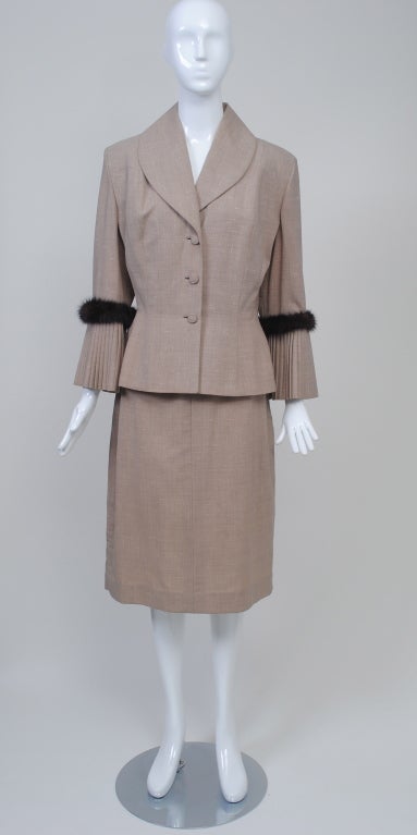 During the 1950s and '60s, Lilli Ann, based in San Francisco, produced some of America's most notable suits and coats, which are coveted today for their dramatic, Hollywood-inspired style and panache. This example has their signature shaped jacket