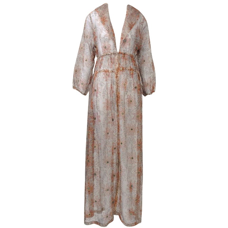 Thea Porter, famous for her lavish textiles influenced by the Near East and crafted into such easy shapes as caftans, created this long, sheer coat c. 1969 out of a handprinted Indian organza. A cocoa background is printed with brown flowers and