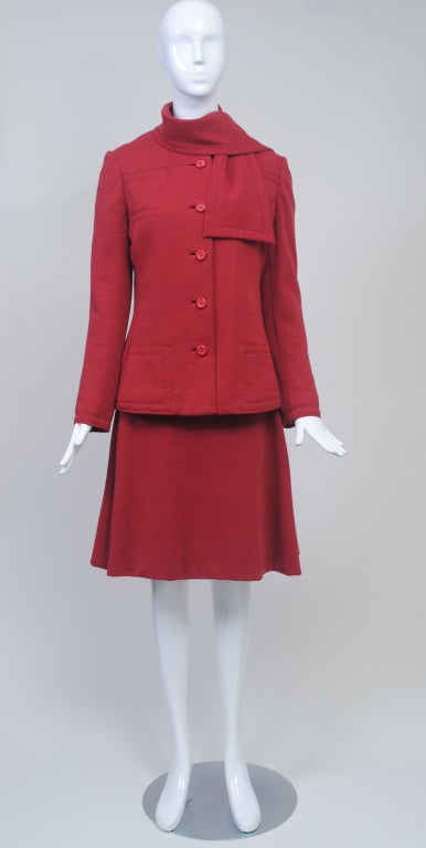 Geoffrey Beene dress and jacket ensemble, c.1972-75,  in rust wool knit. the hip-length jacket is shaped and single breasted and features an attached scarf at the round neckline, as well as very nice detailing of the stitched patch pockets at breast