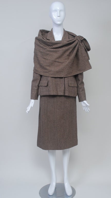 Bill Blass 1980 brown and beige skirt suit with plaid jacket and coordinating check skirt and large shawl. Jacket is double breasted with long lapels and flap pockets. Straight skirt. Large rectangular shawl has loop to pull through end.