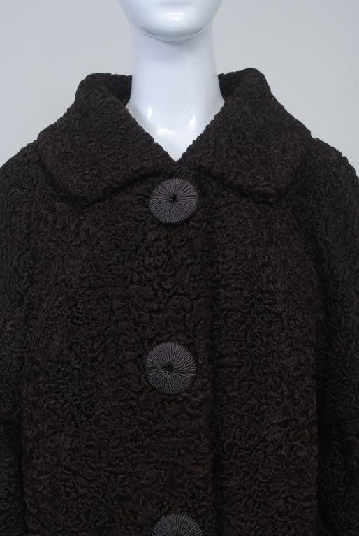 Unusual styling and color for this c. 1960s Persian lamb coat. In a rich chocolate brown, the coat features a high spread collar and horizontal pockets on a straight body. The interest is in the sleeves, which are gathered and belled below the