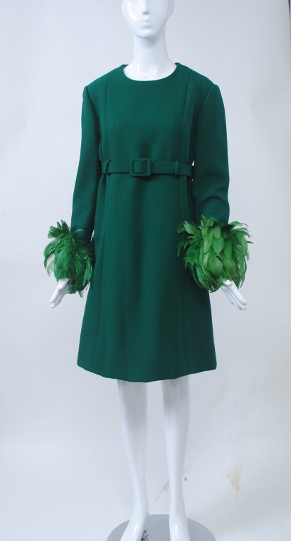 One of a kind piece by Jean Patou Boutique, late 1960s-early 1970s. Constructed of a dense deep green wool crepe in A-line style with empire shaping and self belt and matching feathers around the wrists. Vertical seams from shoulder to hem midway