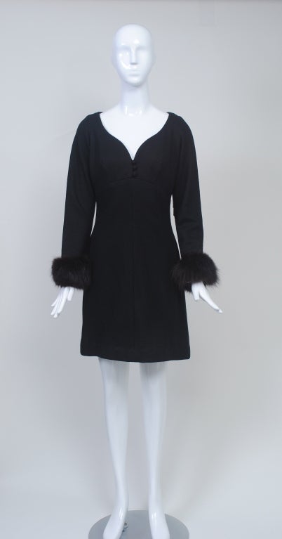 1960s dress features a flattering sweetheart neckline and long narrow sleeves trimmed with dark brown fox. The shaping is empire in front and darts in back. Three self buttons at cleavage, back zipper. A-line skirt. The hem has been doubled over 1