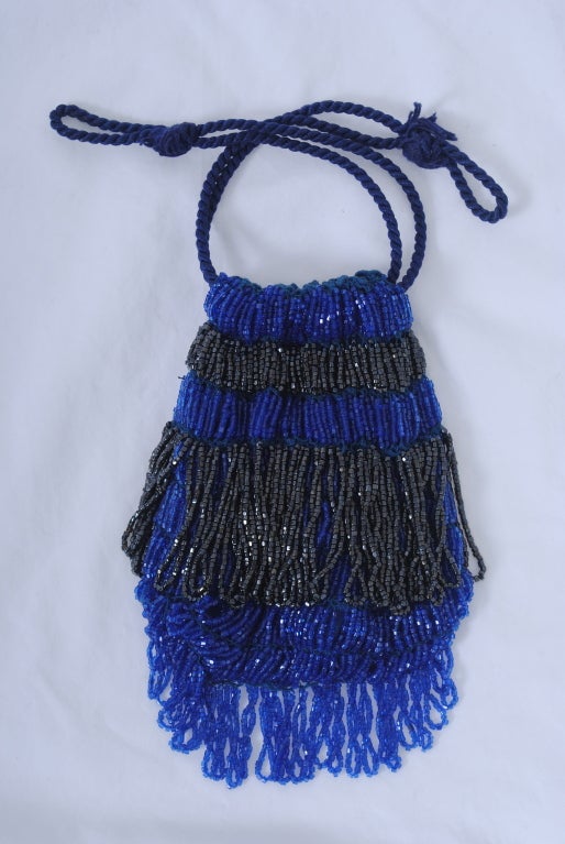 Perlenbeutel aus königsblauen Perlen mit Perlenfransen in Schleifenform und Überlagerungsperlen in Rotguss. Kordelzugverschluss aus gedrehtem Seil.