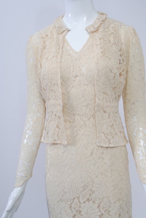 A rare find, this wedding dress and jacket from the 1930s is made of ivory lace and is in excellent condition. The bias-cut dress has a V-neck and empire bodice and features an alluring back with a large cutout; underneath is a separate slip. The