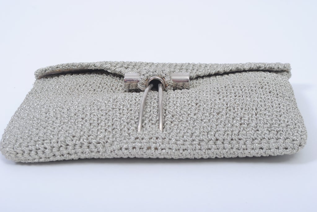 This go-with-everything clutch is perfect for traveling and summer evenings out. Crafted of crocheted silver metallic thread, the envelope-style clutch by Rodo has a unique clasp - a double prong that squeezes into a circular opening at the bottom