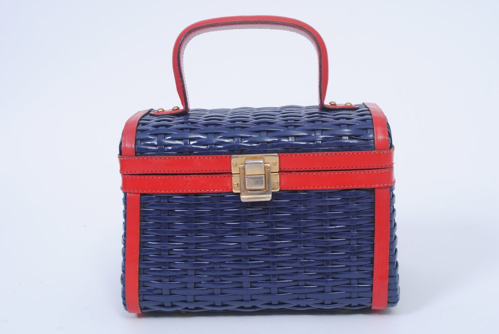 Perk up your July 4th outfit with this outstanding vintage piece. Made by Lewis, the trunk-shaped handbag is composed of dark blue plastic wicker trimmed with red leather, which also makes up the interior. A great 1960s look, in excellent condiition