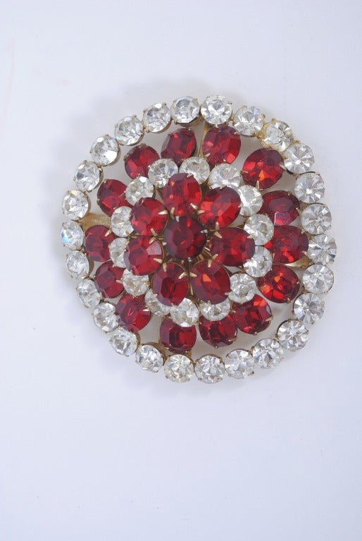 Statement brooch by Coro in red and clear crystals, prong-set in concentric alternating circles that rise towards the center. The clear stones are round, the red are oval, except for the large round center stone. Fabulous on a coat or jacket.