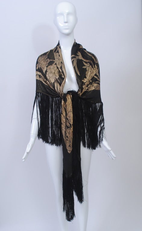1920s black and gold lurex shawl features a large bird and floral pattern, as well as a deep silk fringe. Wear on either side. In excellent condition. Measures 50