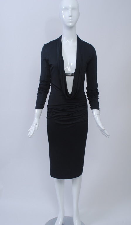 Sophisticated and sexy at the same time, this Ungaro design features a deep cowl neckline that plunges to the waist in front, the cowl held together at the bust line with a tab studded with square clear stones. The body hugging dress is composed of