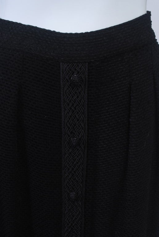Wear this classic Chanel skirt day or evening. Crafted of a mini-chenille fabric of wool and rayon, the skirt reaches almost to the ankle. It is trimmed with a braided border along the faux button-down front and around the hem. Back zipper. Fully