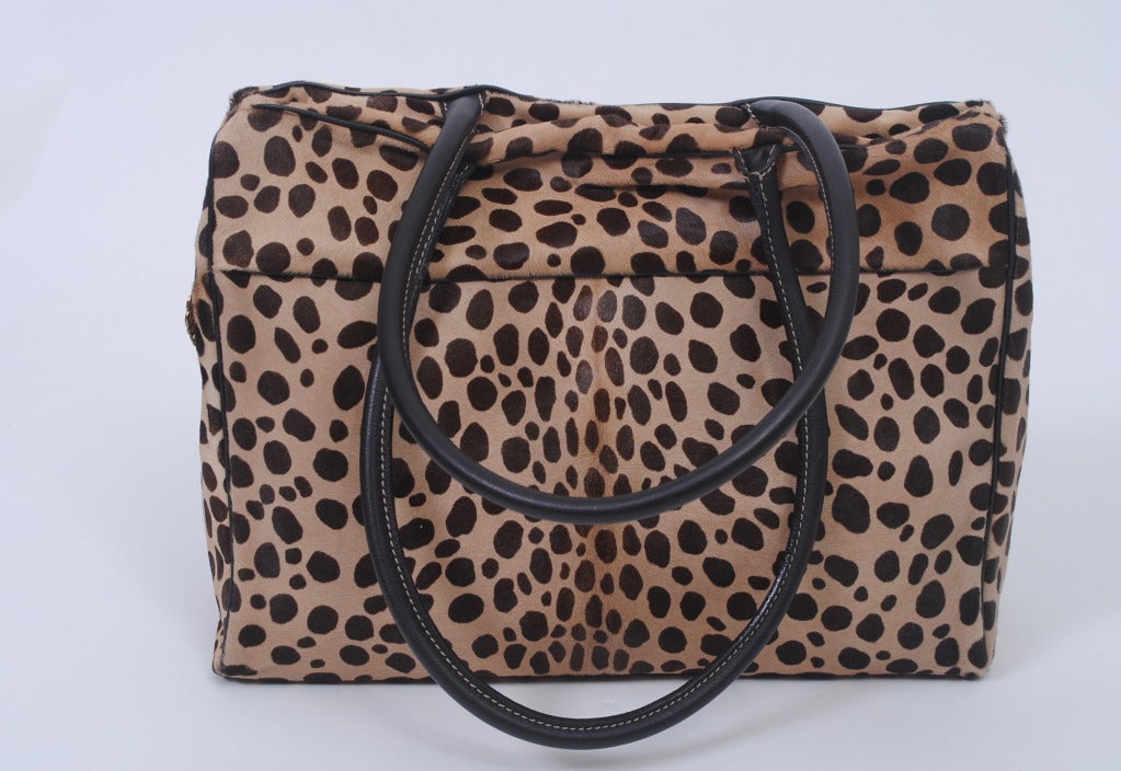 A large tote in leopard-spotted pony skin by Redwall for Moschino. The bag features a long zip top, as well as black leather double-loop handles and bottom. Roomy open interior with side zip compartment. In original dust bag; appears unworn.