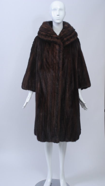 Mahogany mink coat in modified swing style with shawl collar and bracelet-length sleeves. One button at neck. Wear as is or with a wide belt cinching the waist. S-M.
