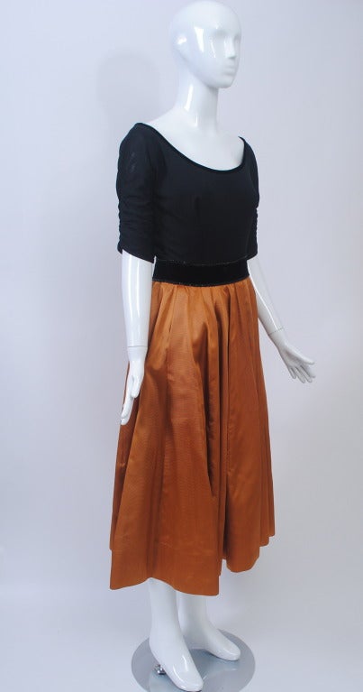 Unique two-piece evening outfit consisting of a black matte jersey top and a copper silk faille circle skirt. The bodice has a wide off-the-shoulder neckline trimmed in black velvet and shirred three-quarter sleeves, zipper on the side. The full