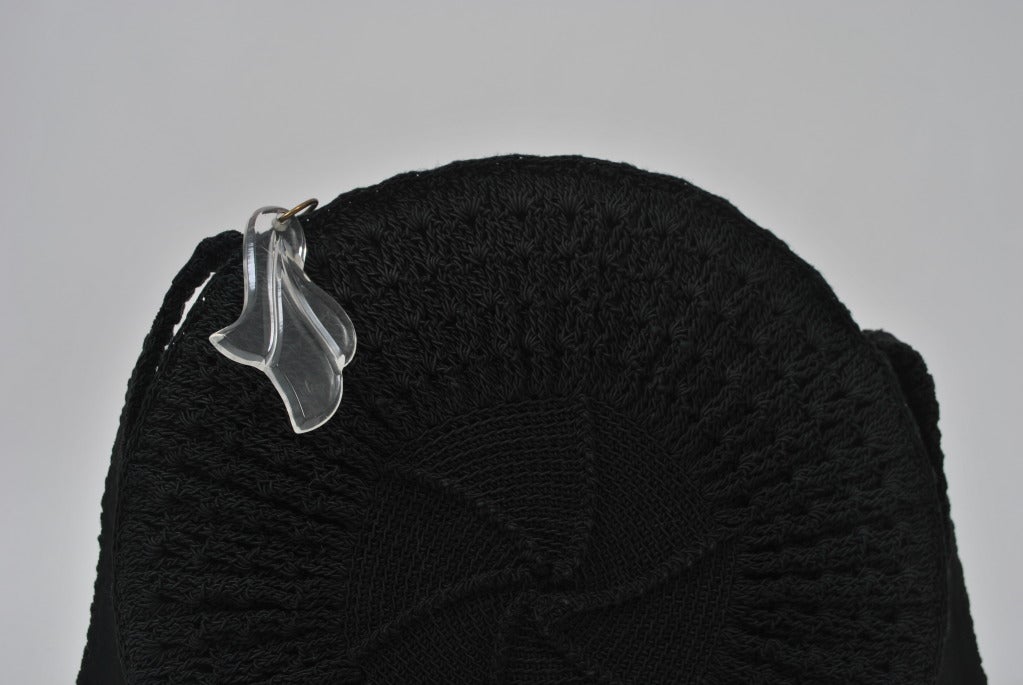 Very unusual to find a shoulder bag in this genre, and especially in this circular shape. Body and shoulder strap is crocheted in black, fully lined, with zip compartment. Metal zipper across top with lucite, leaf form pull. Handle length is 41