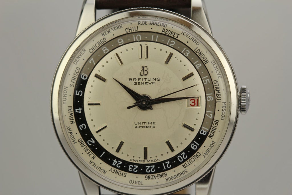 This is a rare Breitling Unitime World Time wristwatch. The round case in stainless steel with snap back, faceted lugs, and a rotating bezel with the cities indicated. Two-tone matte silvered dial, the twenty-four hour (day/night), the cities around