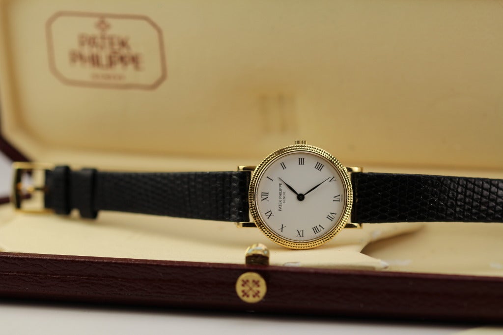 Patek Philippe Lady's 18k yellow gold Calatrava wristwatch, Ref 4819. This watch has a white dial with Roman numerals, feuille hands, hobnail bezel, 25mm case, on a Patek Philippe leather strap, yellow gold tang Patek Philippe buckle, and has a