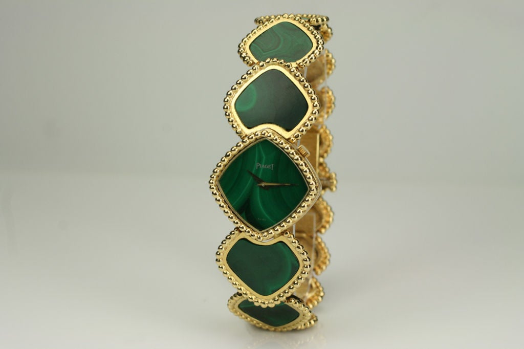 Piaget 18k yellow gold and green malachite dress watch. This has a manual wind movement, 26mm x 27mm diamond shaped screw down case, green malachite dial, no markers, gold dauphine hands, sapphire crystal, beaded bezel, integrated 18k YG/green