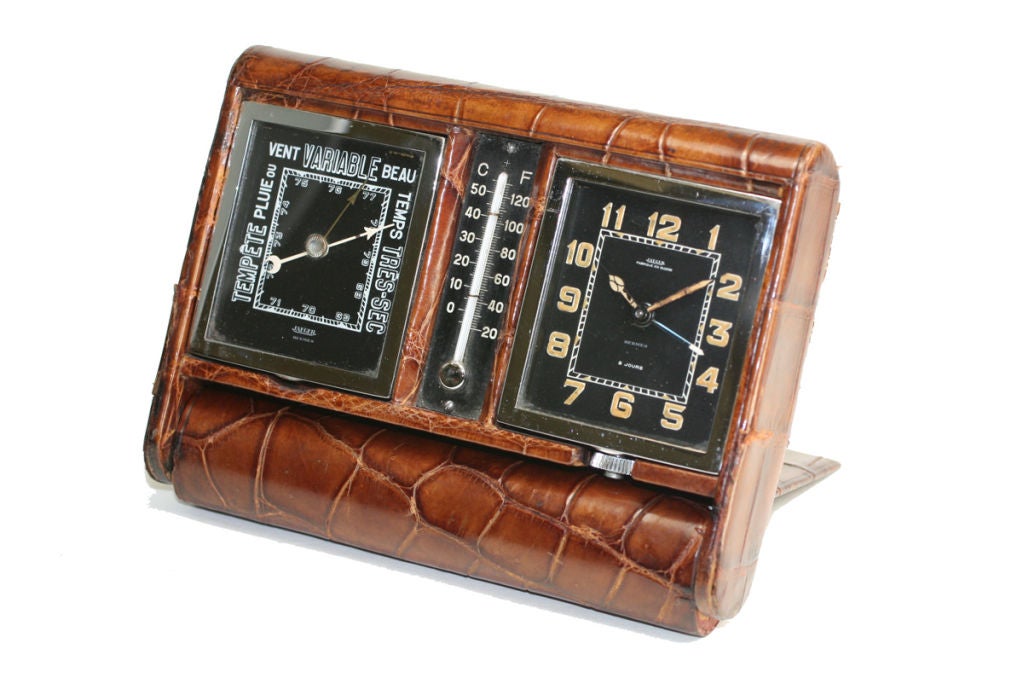 The is a gorgeous vintage Jaeger travel alarm clock that was made for the retailer Hermes. The folding case is made of a beautiful honey crocodile with the alarm clock on one side, temperature, and Barometer gauge on the other.