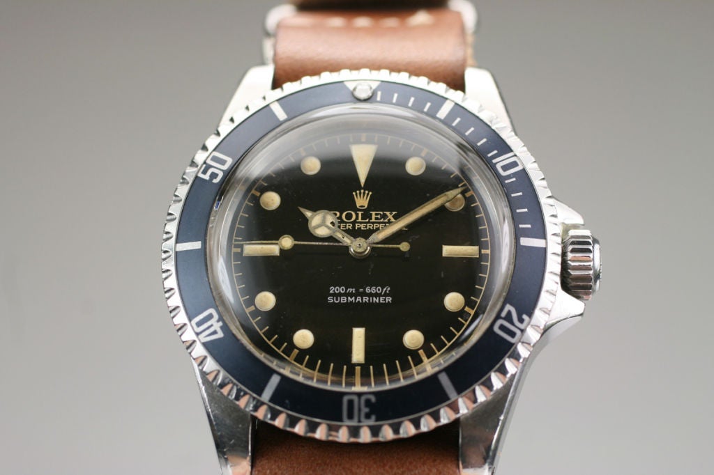 This is a great looking example of a very collectible early 1960s Rolex Submariner reference 5513. It has an original and rare gilt dial with gold and silver writing and the outer railroad scale. The early case is in excellent condition maintaining